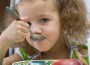 The girl has breakfast corn flakes with milk, over white